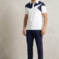 Man wearing a white and navy sports outfit with a logo on a plain background