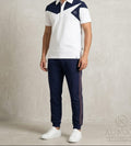 Man wearing a white and navy sports outfit with a logo on a plain background
